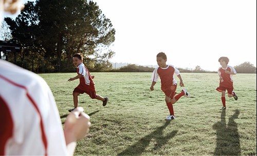 Boys playing soccer on soccer field in their kit