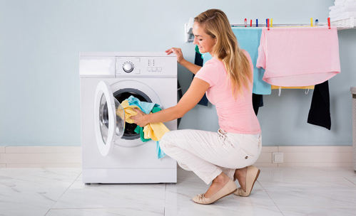 Woman putting washing into a tumble dryer