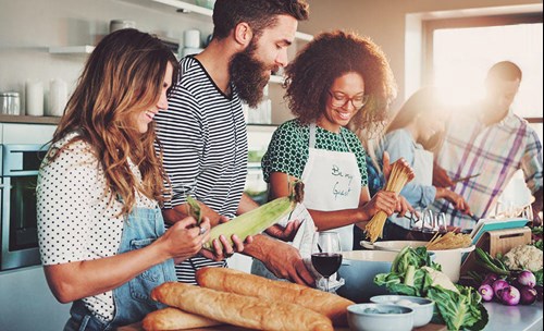 A group of people making food together, smiling