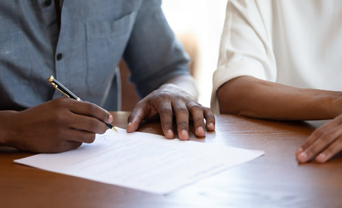 Man signing a paper with woman sitting next to him