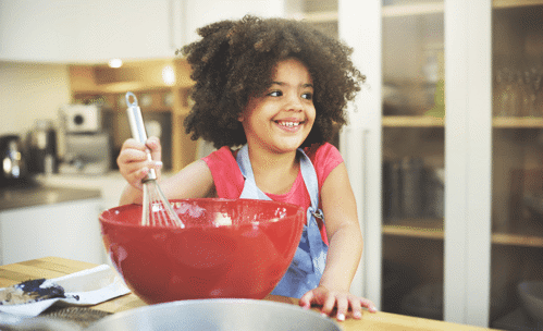 Smiling girl whisking something in a mixing bowl
