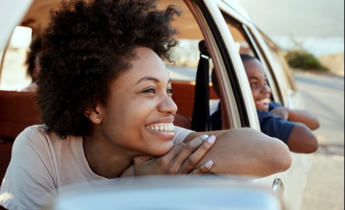 Laughing woman and boy looking out of the car, leaning out of their windows