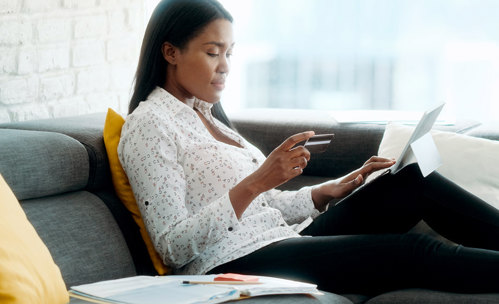 Woman sitting on couch with bank card