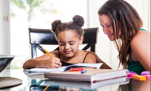 Woman helping girl with homework at a table