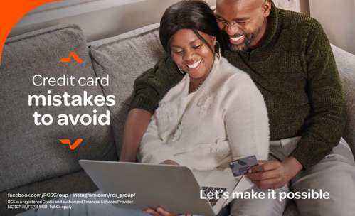 Couple on couch, smiling at a laptop and man holding a card