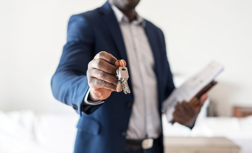 Man in suit holding keys in the air