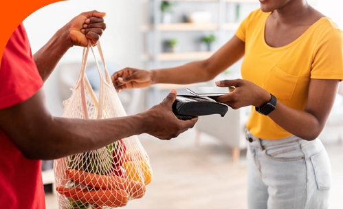 Woman paying for groceries with card on card machine.