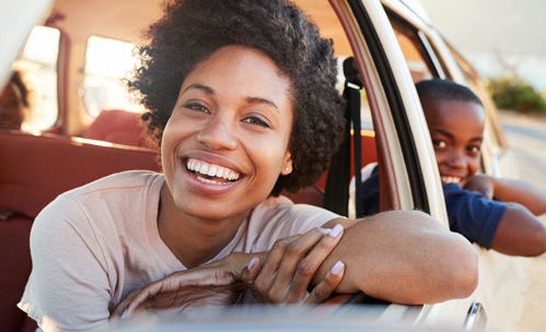 Woman and boy in car, smiling while leaning out of their windows