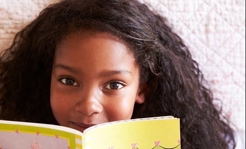 Smiling girl, with a book in front of her