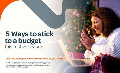 Woman siiting with laptop on her lap, clapping hands, and Christmas tree in the background