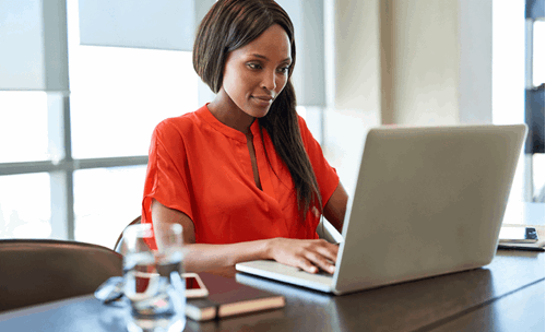 Woman with orange top on working on laptop