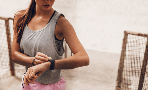 Woman in active wear, looking at her smartwatch